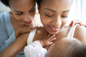 Zwei Frauen halten glücklich ihr Baby im Arm