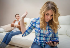Jugendliche schaut auf Handy und ignoriert Mutter