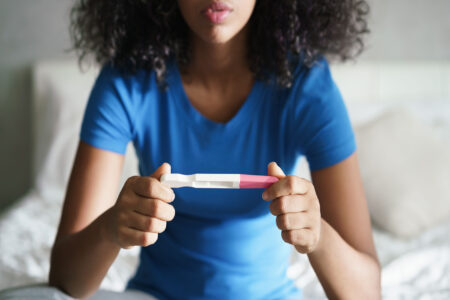 Jugendliche blickt auf Schwangerschaftstest