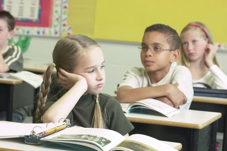 Trauriges Mädchen sitzt am Tisch in der Klasse