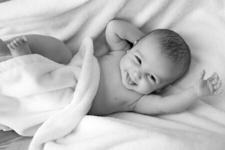 Fröhliches Baby liegt auf Decke