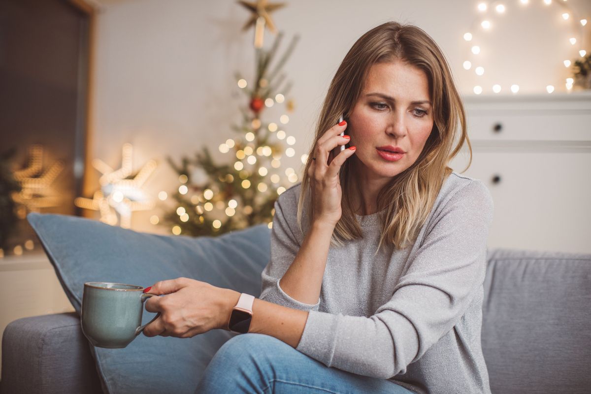 Traurige Frau telefoniert auf dem Sofa