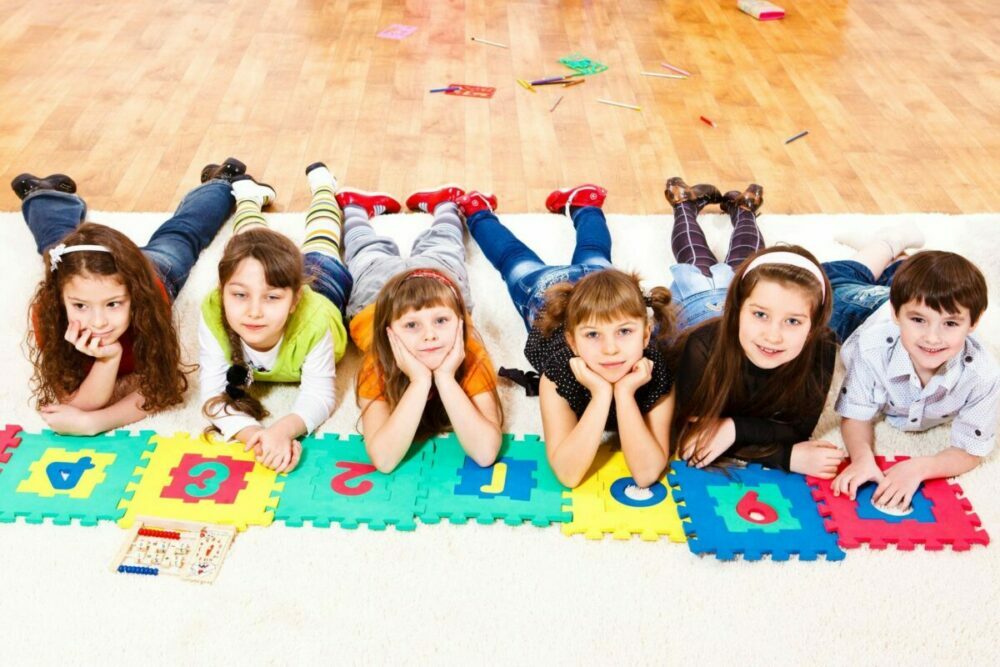 Gemischte Kindergruppe im Grundschulalter liegt auf dem Bauch